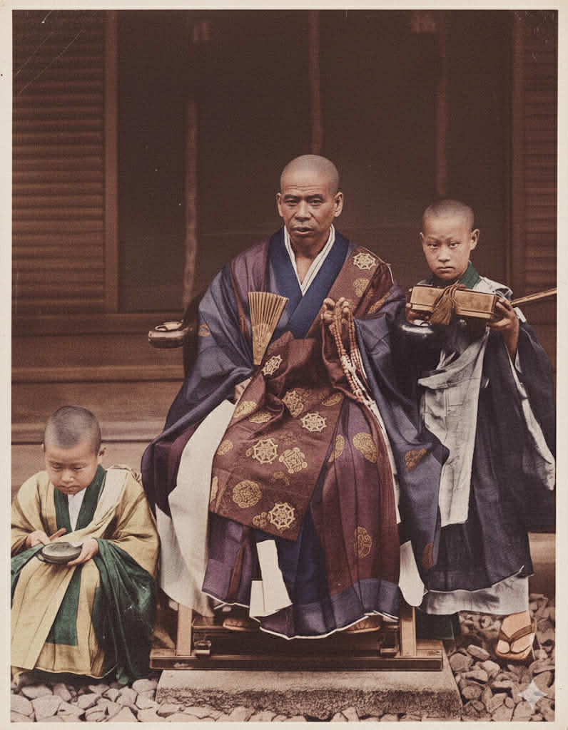 Colored photograph of a Japanese Buddhist monk seated between two novice boys, c. 1895–1910.